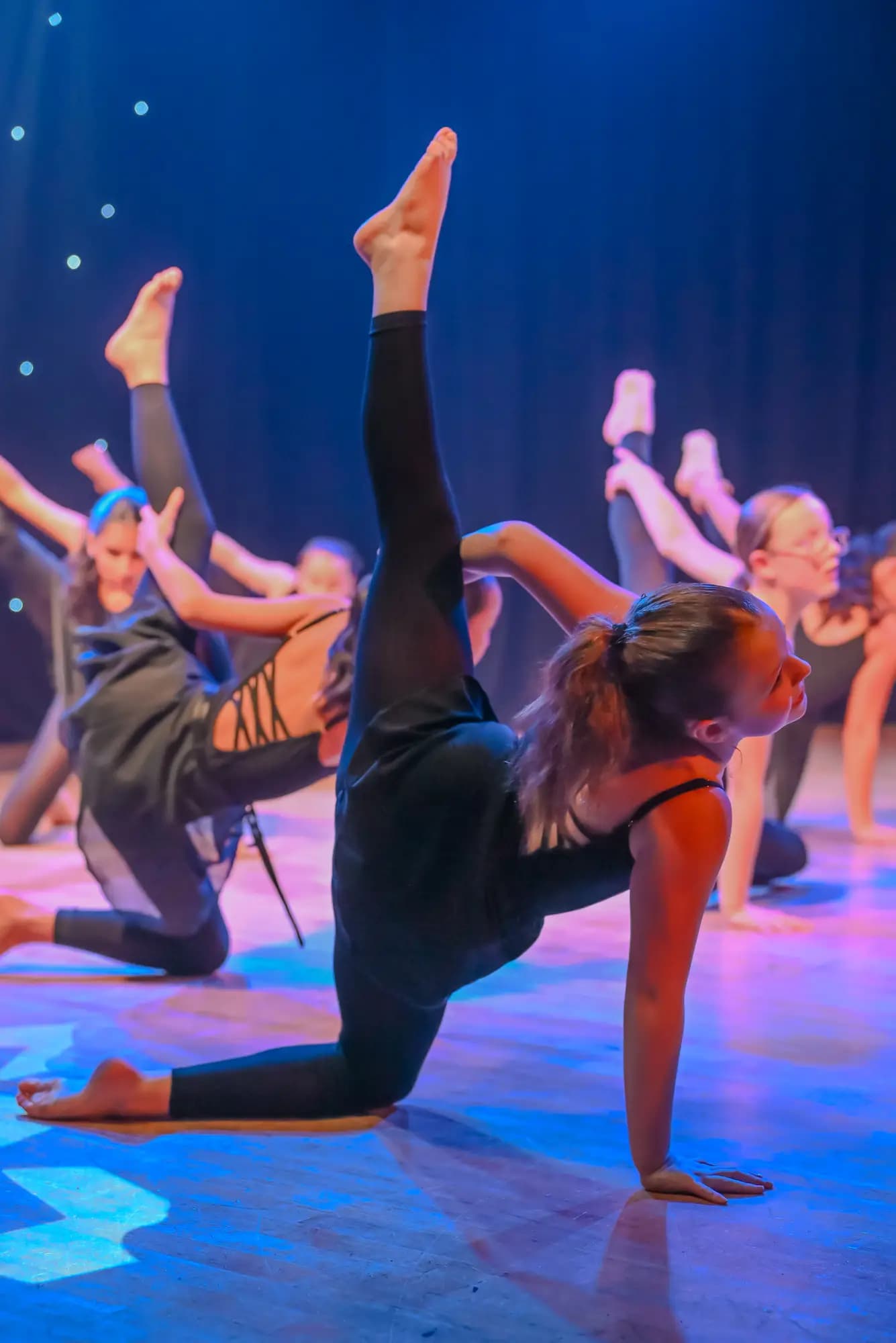 Contemporary dancers in a stage leg-hold formation