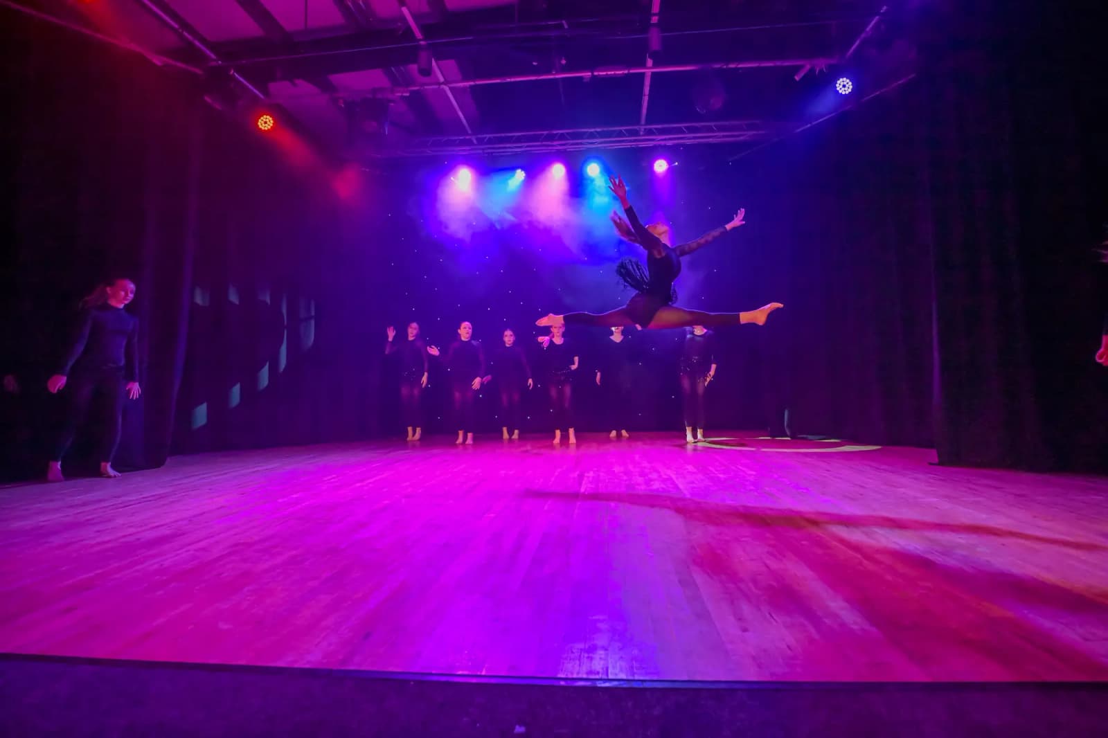 Dancer mid-air in a split leap on stage