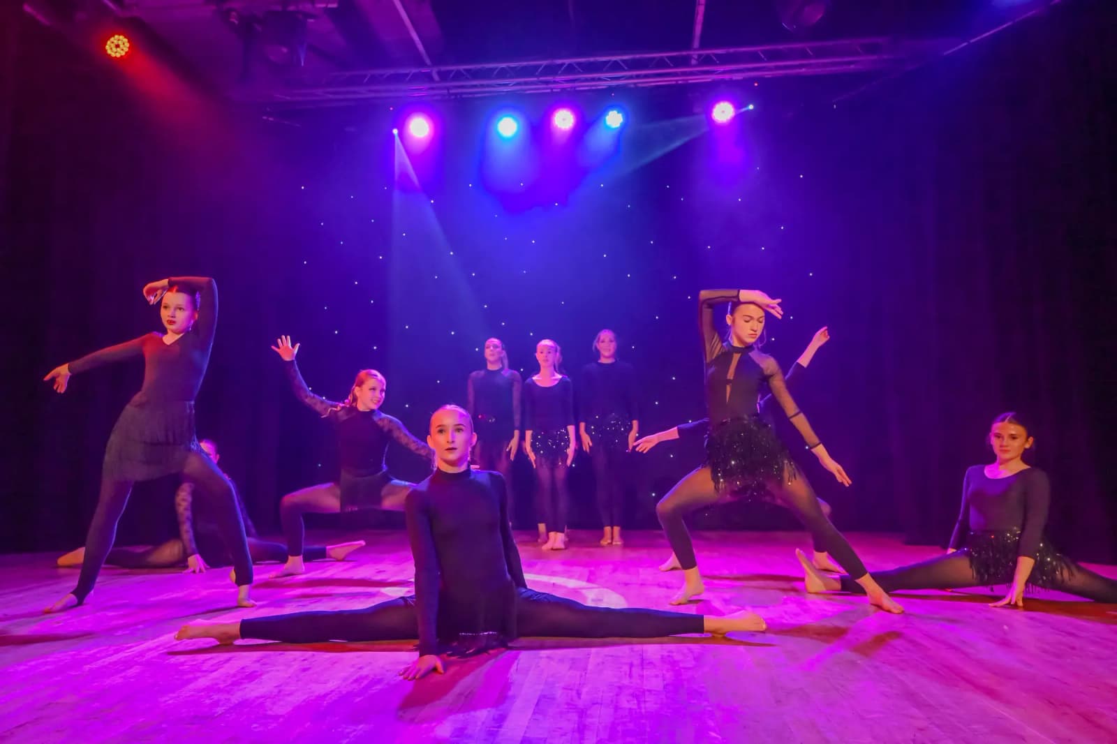 Group routine with a dancer in box splits centre stage