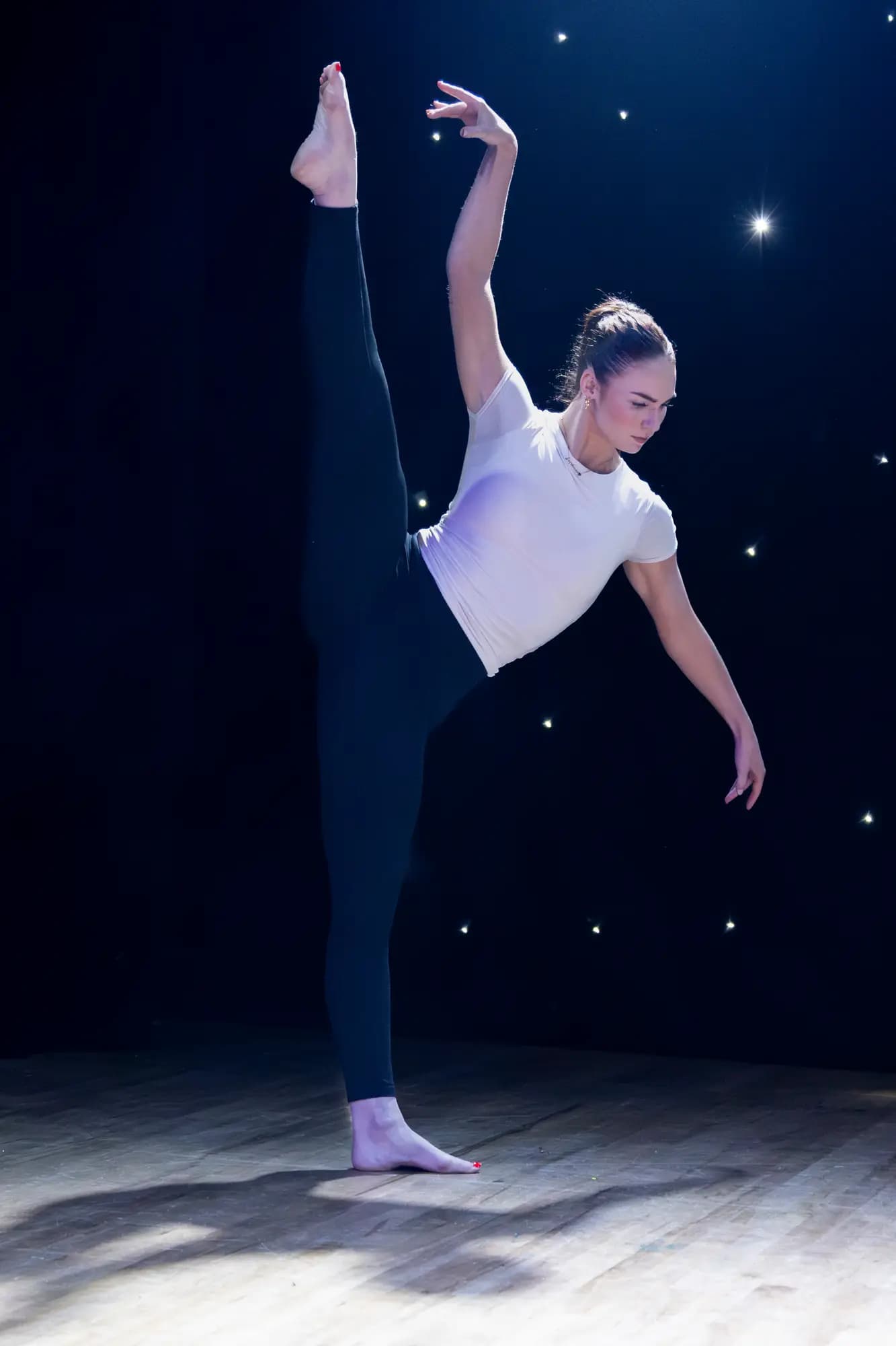 Sophie in a contemporary solo, leg extended high on stage