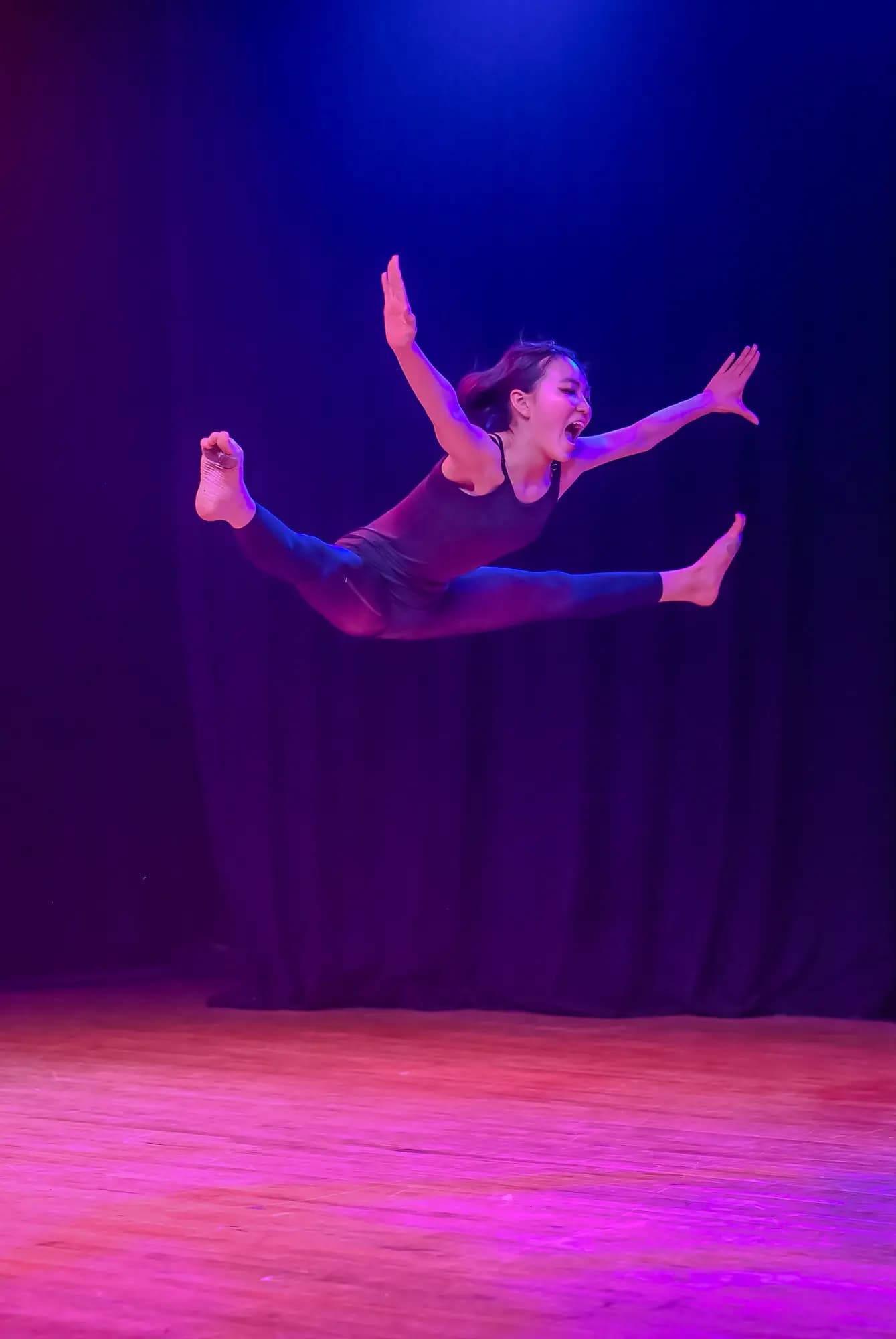 Dancer in a dynamic mid-air leap on stage