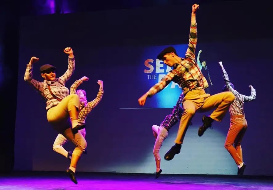 Star-Struck dancers mid-leap on stage